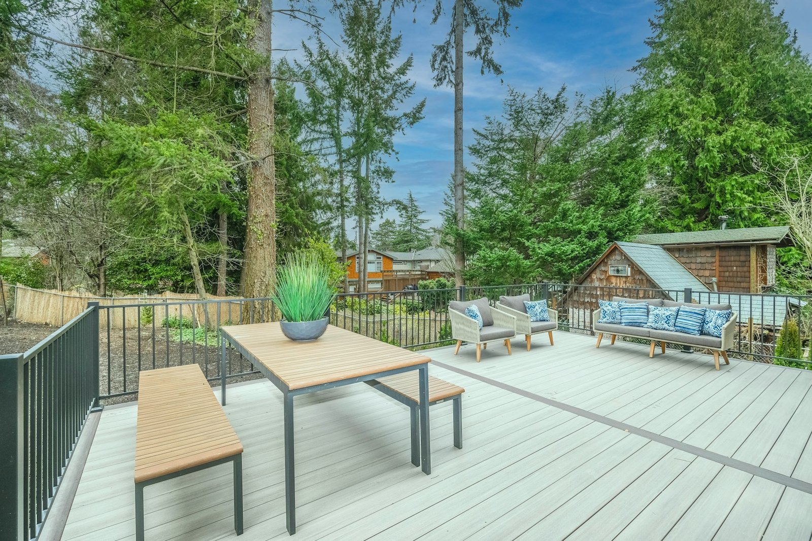 Composite deck boards with a table and chairs beside a black metal railing